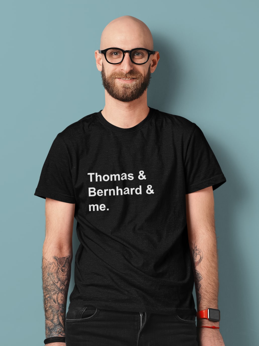 ein tätowierter Mann mit Brille im schwarzen T-Shirt in einem Studio